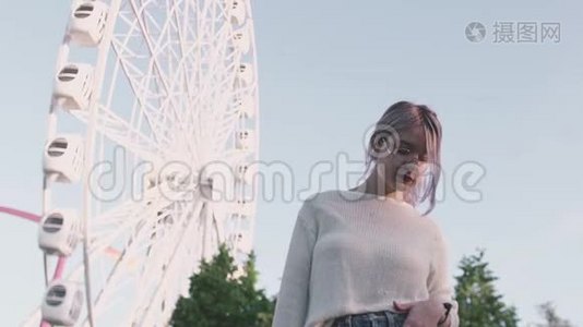 戴眼镜的漂亮女孩站在愤怒公园的摩天轮下视频