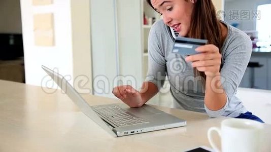 一个漂亮的黑发女人在网上购物，一边打电话视频