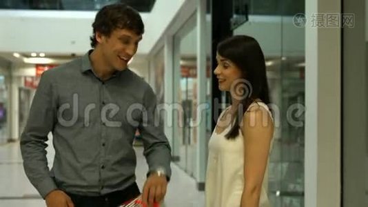 微笑的夫妇在购物中心讨论视频