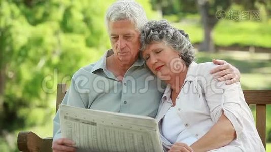 成熟的男人一边看报纸一边拥抱妻子视频