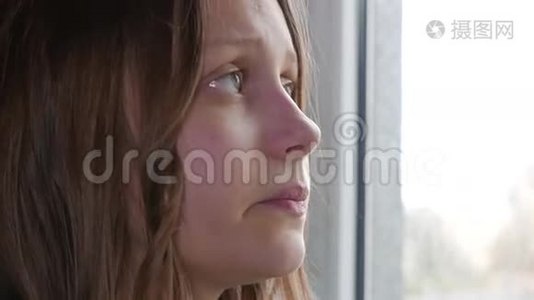 家里很郁闷。 伤心的女孩靠近窗户。 4KUHD。视频