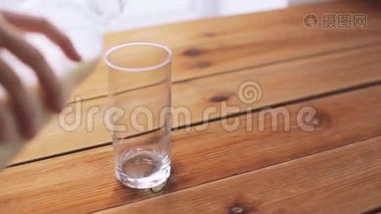 用手将牛奶倒入木制桌子上的空玻璃中视频