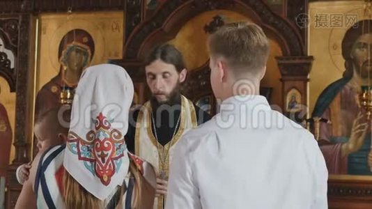 牧师在洗礼仪式上为带着孩子的父母朗诵祈祷词视频