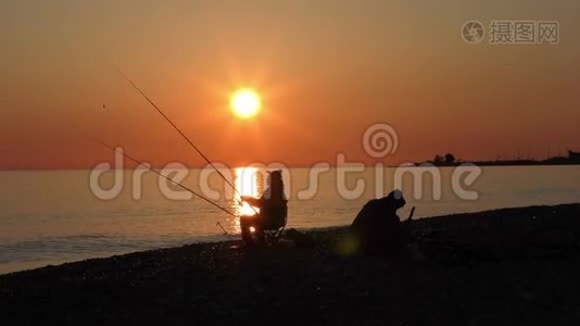 美丽的景色与渔夫剪影与鱼竿坐在海边视频