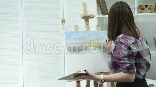 穿围裙的年轻女艺术家在艺术工作室画画布视频