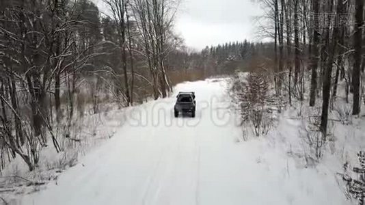 越野车6x6在雪地森林的冬季道路上行驶，后景视频