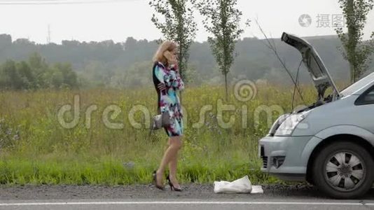 一个美丽的女孩在乡间小路上的破车旁打电话视频