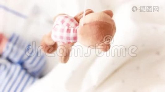 顶部的照片，可爱的婴儿与另一个躺在婴儿床和看旋转的小熊玩具视频
