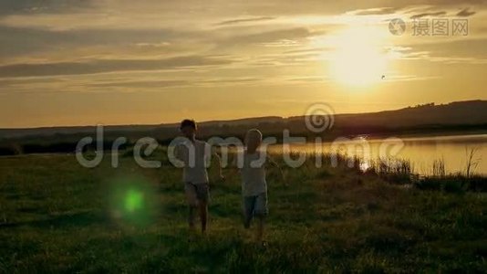 两个快乐的孩子在公园里跑来跑去。 在田野上，两兄弟正在日落时分玩耍视频
