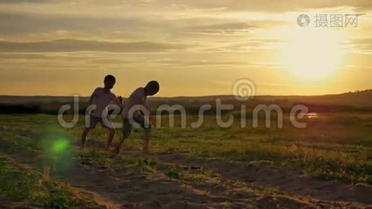 两个快乐的孩子在公园里跑来跑去。 在田野上，两兄弟正在日落时分玩耍视频