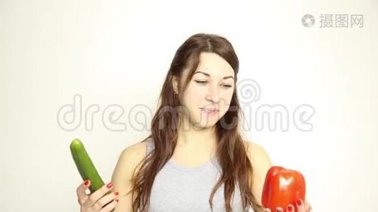 美丽的年轻女人吃蔬菜。 拿着黄瓜和红胡椒。 健康食物-健康身体概念视频