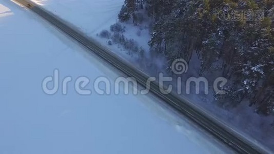 一辆车在乡村公路上穿过冬季森林。 从无人驾驶飞机俯视。 穿过森林的道路的鸟瞰图视频