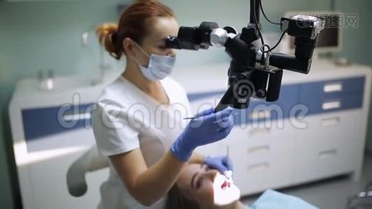 女性牙医用牙科工具-显微镜，镜子和探针治疗病人牙齿在牙科诊所办公室。 医药视频