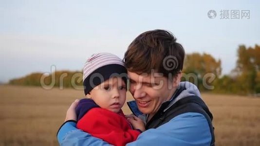 一个年轻的父亲把他的孩子抱在怀里。 温柔和怀抱的挚爱父亲.. 户外活动视频