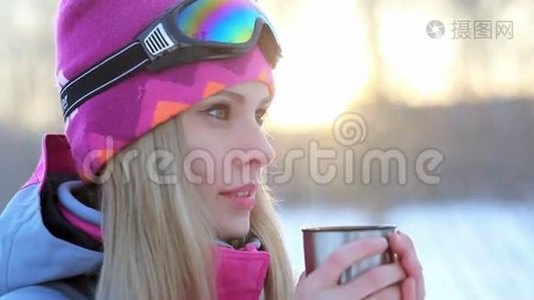 女人手里拿着热水瓶里的杯子，在雪白的树枝上喝茶视频