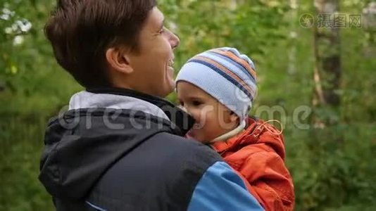 一个年轻的父亲把他的孩子抱在怀里。 温柔和怀抱的挚爱父亲.. 户外活动视频