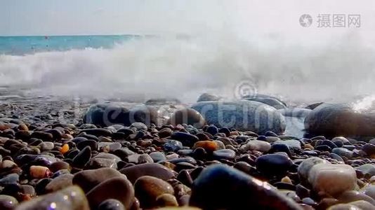 卵石海滩，小卵石和海浪。 船在海上。 海的表面在一个野生鹅卵石海滩上。 波浪是视频