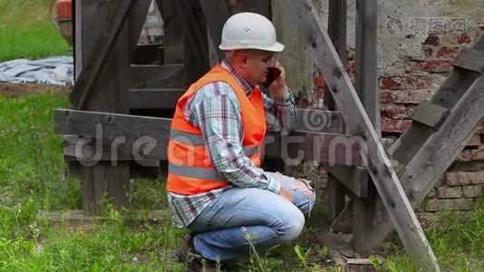 建筑工人检查木脚手架和智能电话交谈视频