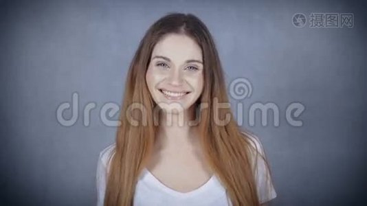 幸福的年轻女人，在灰色的背景下，带着完美的微笑。视频