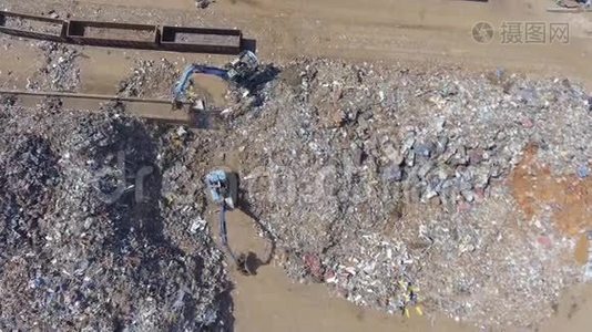 铁原料回收堆，工机.. 金属废料垃圾场。 挖掘机在垃圾场工作。 从这里看视频