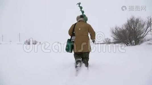 一个渔夫走在一个白雪覆盖的湖上，寻找一个好的。视频