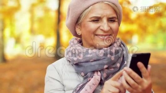 秋天公园有智能手机的快乐高级女人视频