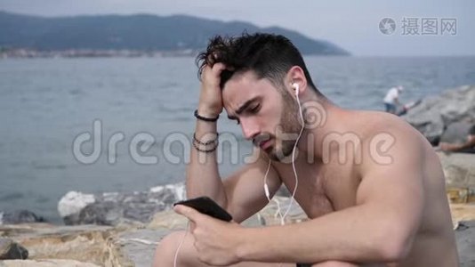 海滩上的年轻人用耳机听音乐视频