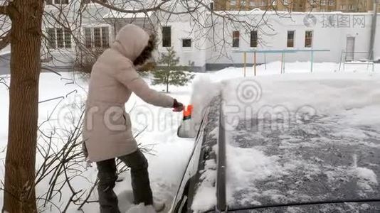 女青年在暴风雪后用刮泥机清洗汽车视频