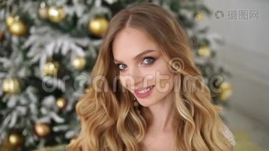 一幅美丽的笑脸女人的画像，她的发型和化妆把她可爱的婴儿抱在装饰好的圣诞树上视频