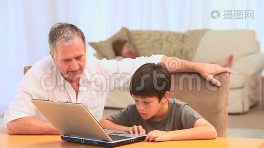 一位祖父和他的孙子用笔记本电脑视频