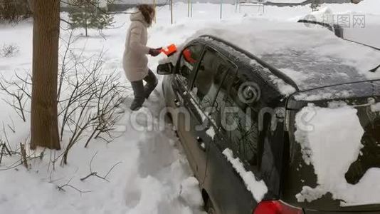 女青年在暴风雪后用刮泥机清洗汽车视频