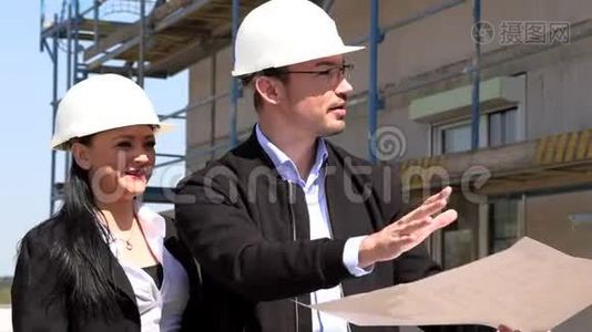 两名戴白盔的建筑师在工地上讨论一项计划视频