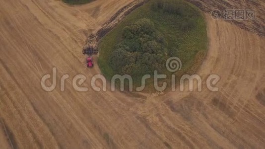 空中：在耕地上向无人机射击。一辆红色拖拉机在秋天开垦田地视频