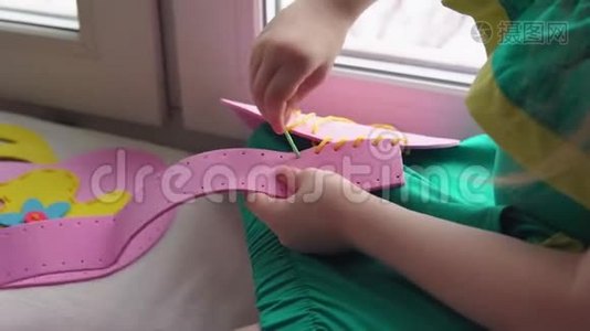 可爱的小女孩缝一个粉红色的手提包。视频
