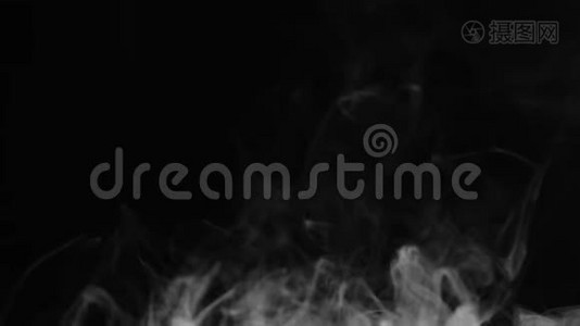 现实的抽象烟雾蒸气效应从底部。 白色烟雾在黑色背景上缓慢运动。 漂浮的雾云。视频