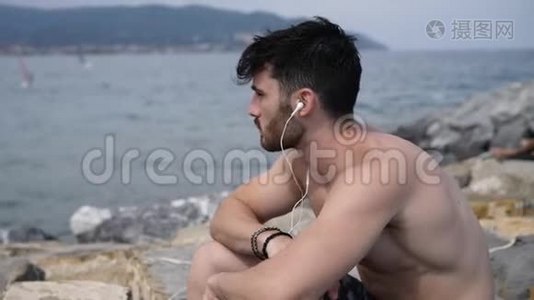 海滩上的年轻人用耳机听音乐视频