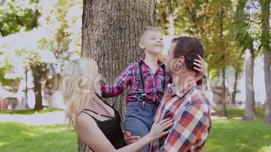 幸福快乐的家庭在公园的树旁拥抱和微笑。视频
