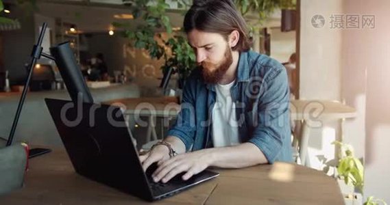 男子在咖啡厅的笔记本电脑上工作视频
