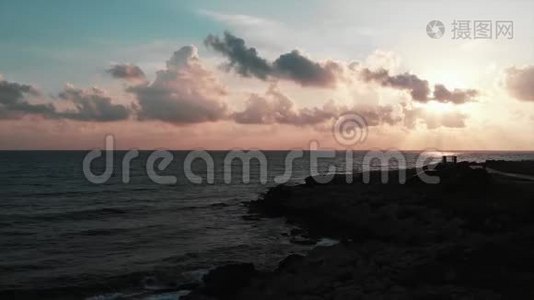 带海洋和岩石海滩的美丽粉红色日落的空中景色视频