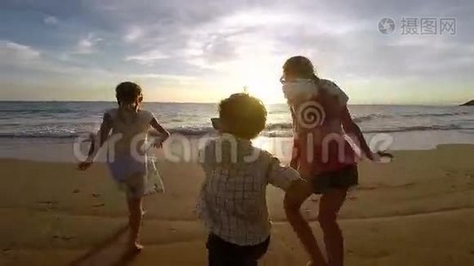 快乐的孩子们在日落时在海滩上玩耍。视频