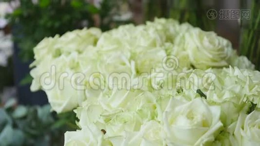 在花店里，用一束束绿色的茎叶组成的白色鲜玫瑰特写镜头出售视频