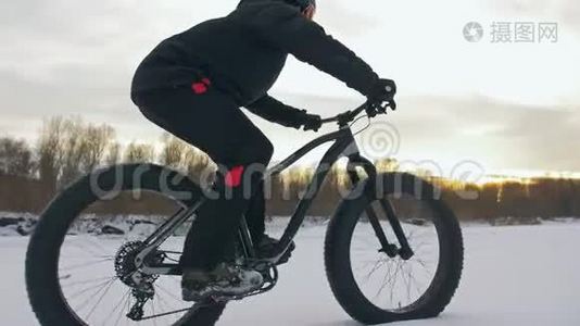专业的极限运动员骑自行车在户外骑胖自行车。 骑自行车在冬天的雪林里。 男人是审判视频