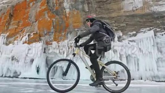 人正骑自行车在冰窟附近。 有冰洞和冰柱的岩石非常美丽。 骑自行车的人穿着视频