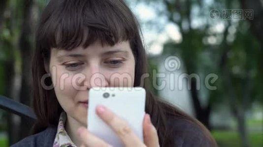 一个年轻女人使用智能手机的肖像，她自拍。视频