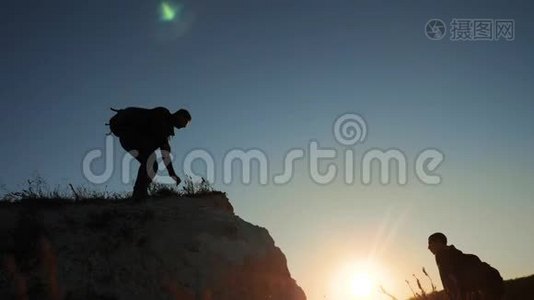 两个男子协同游客爬上一座山。 徒步旅行者徒步旅行冒险登山日落攀登视频