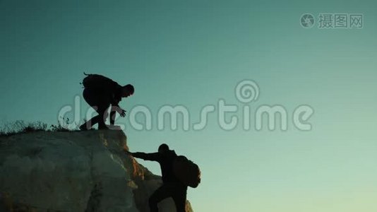 两个男子协同游客爬上一座山。 徒步旅行者徒步旅行冒险登山日落攀登视频