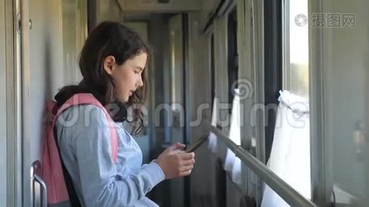 小女孩带着背包和智能手机在火车车厢里散步。 旅游运输铁路概念视频