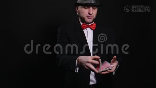 年轻魔术师在黑色背景下表演魔术纸牌魔术表演概念魔术视频