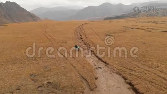 一对戴着帽子和太阳镜的大背包的旅行者男女在高山上漫步的鸟瞰图视频