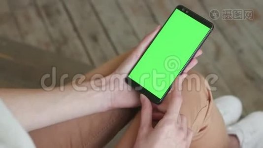 家中年轻女性移动智能手机的绿色屏幕视频